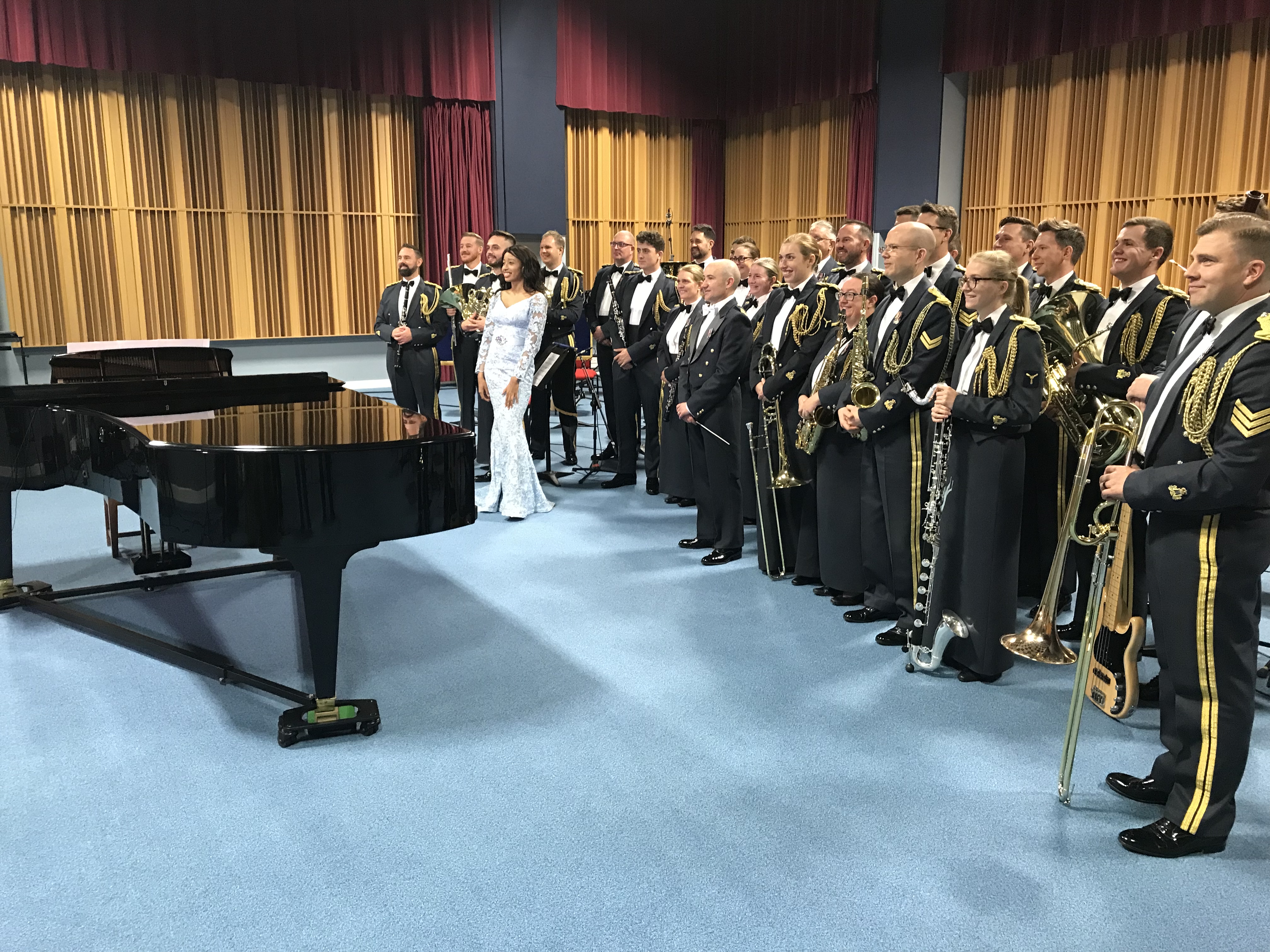 Ify and the RAF Musicians stand by a grand piano. 